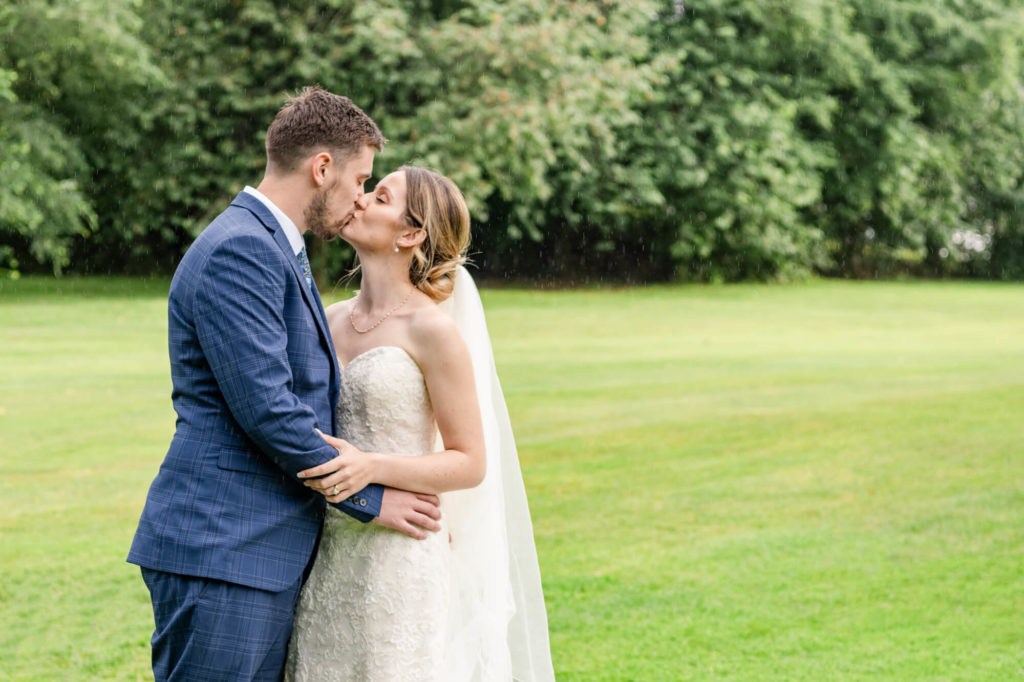 Top tips for a rainy wedding day from a photographer. A newly married couple in the rain in The Cotswolds