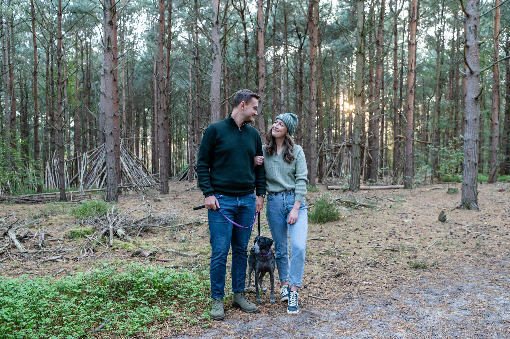 A sunset couple photoshoot at Woburn Woods in Milton Keynes. A couple in the woods with their dog