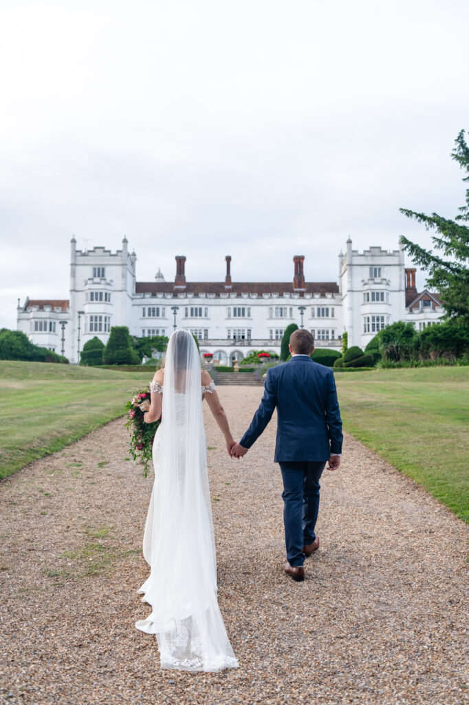 Couple hand in hand outside of their Danesfield House wedding venue