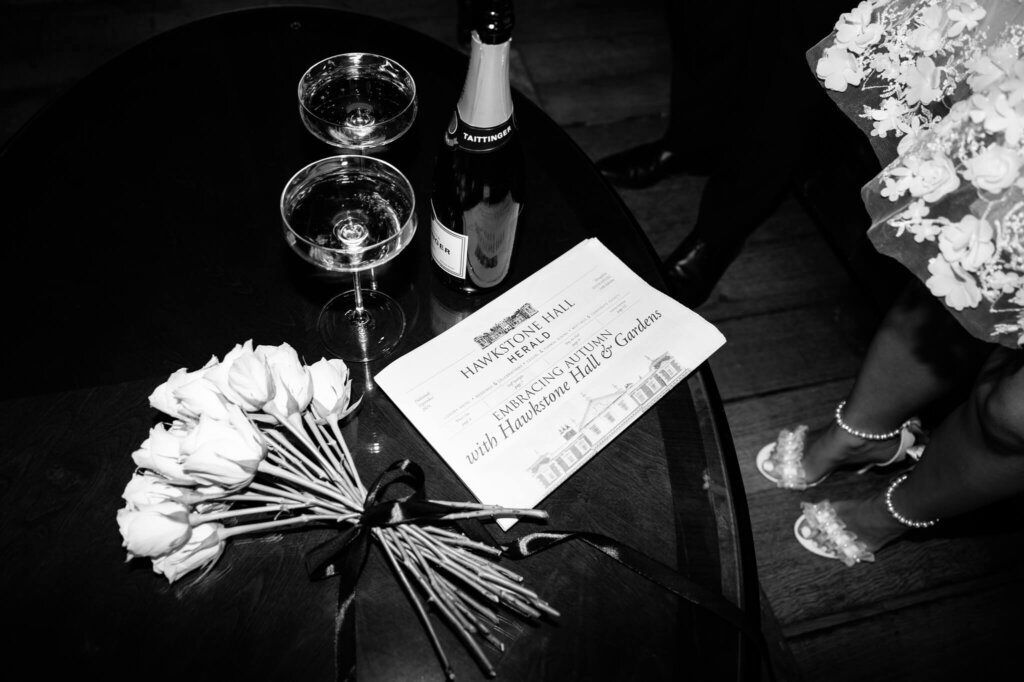 Editorial wedding photography at Hawkstone Hall. Black and white flash photo of the Hawkstone Hall Herald, white roses and champagne