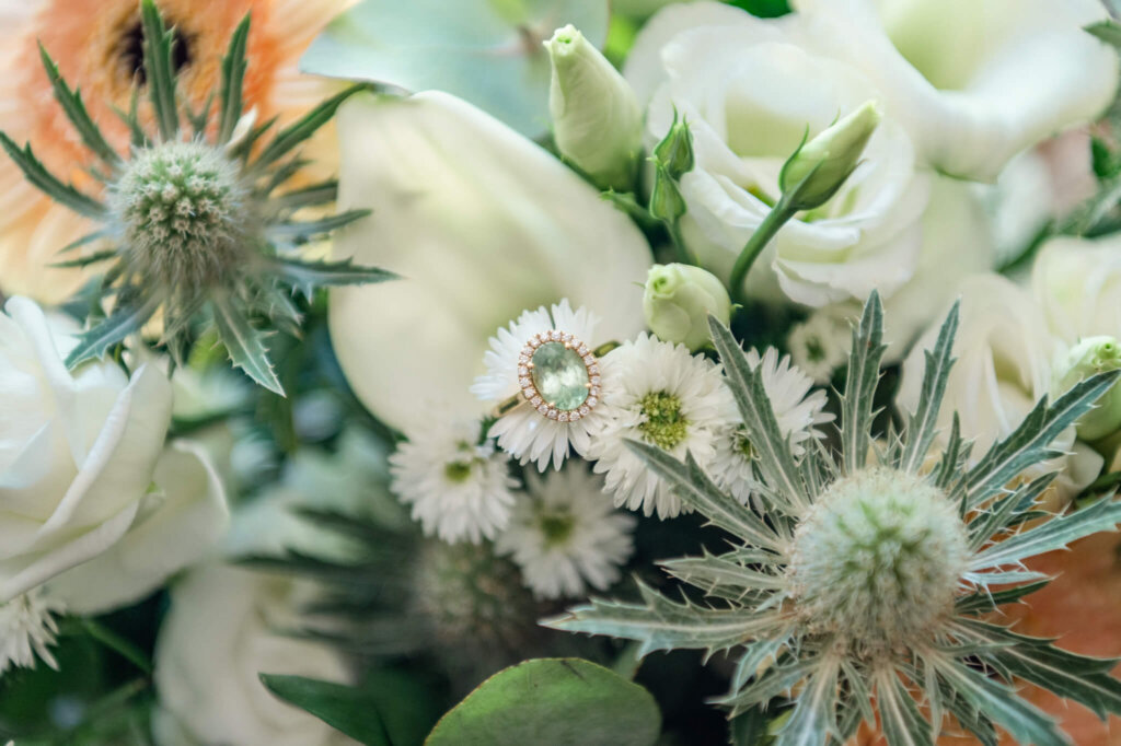 A stunning green stone engagement ring on a bouquet of flowers